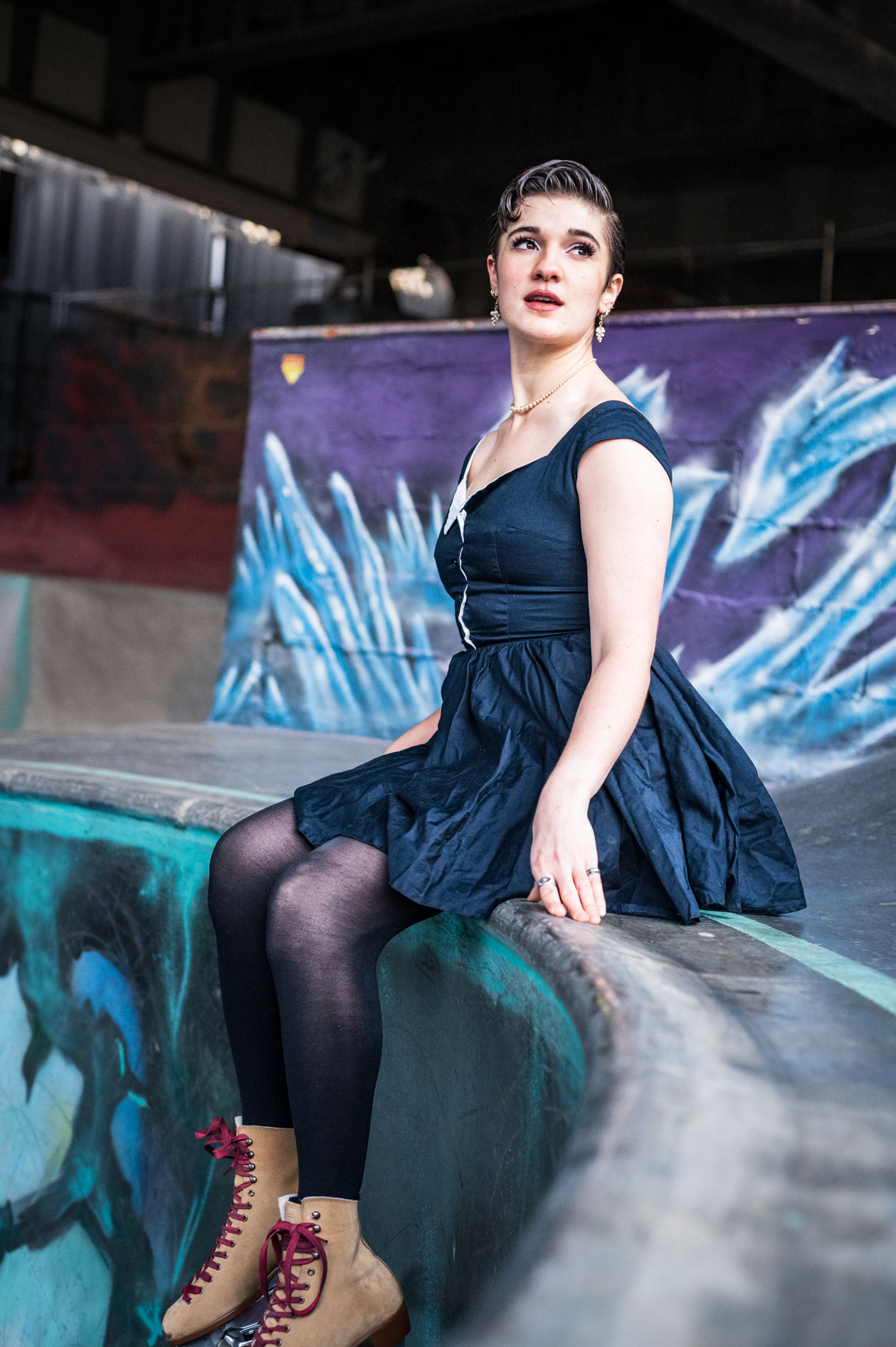 An inclusive portrait of a nonbinary model, Ana Gonzalez, wearing a dress and roller skates, sitting in a skate park in Portland, Oregon.