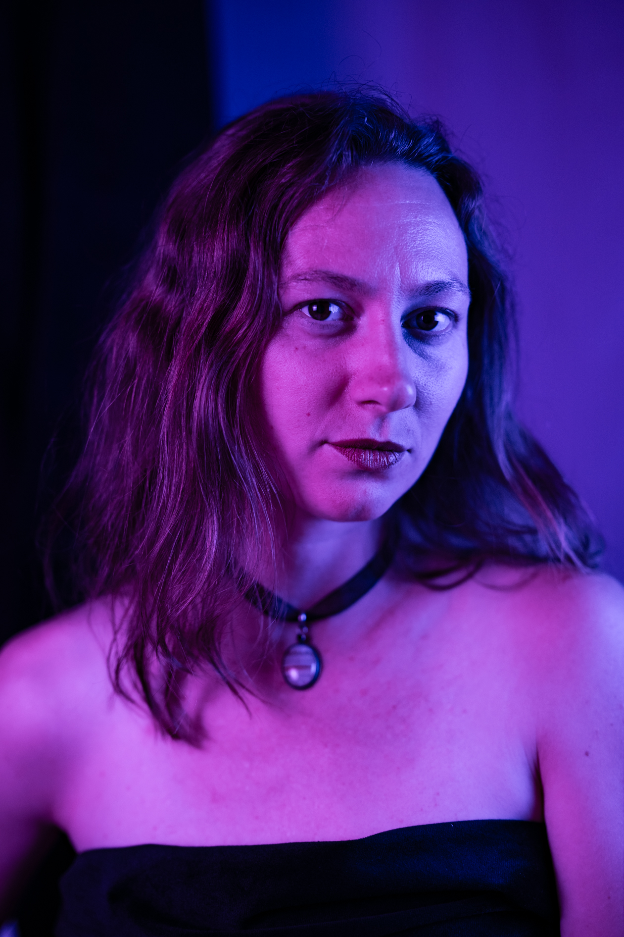 A dramatic studio portrait of Rosalyn Fey under vibrant purple and blue lighting. This image showcases inclusive portraits in Portland, Oregon.