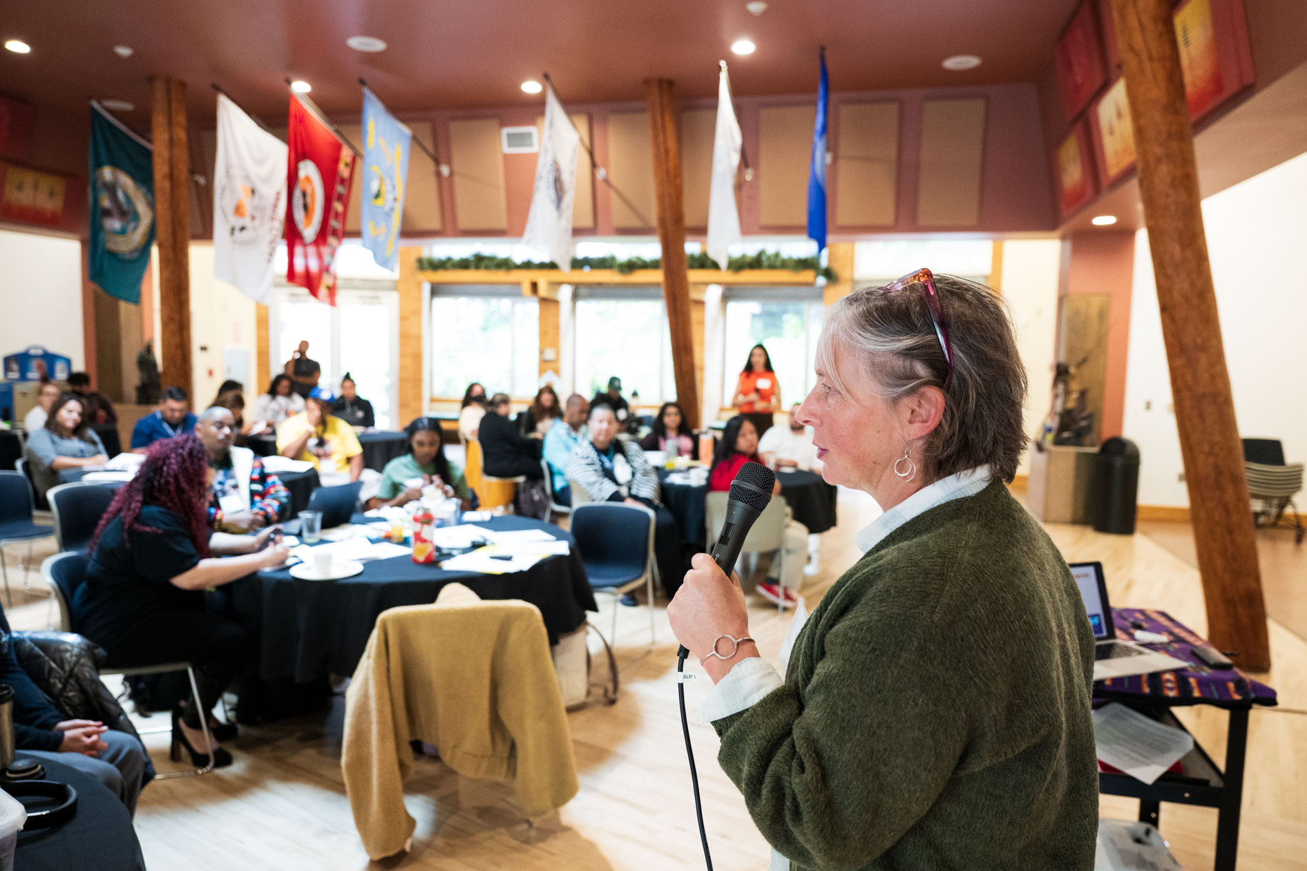 A candid photograph of a speaker addressing a room full of Northwest Health Foundation JREP grantees at a convening event. This showcases nonprofit event photography.