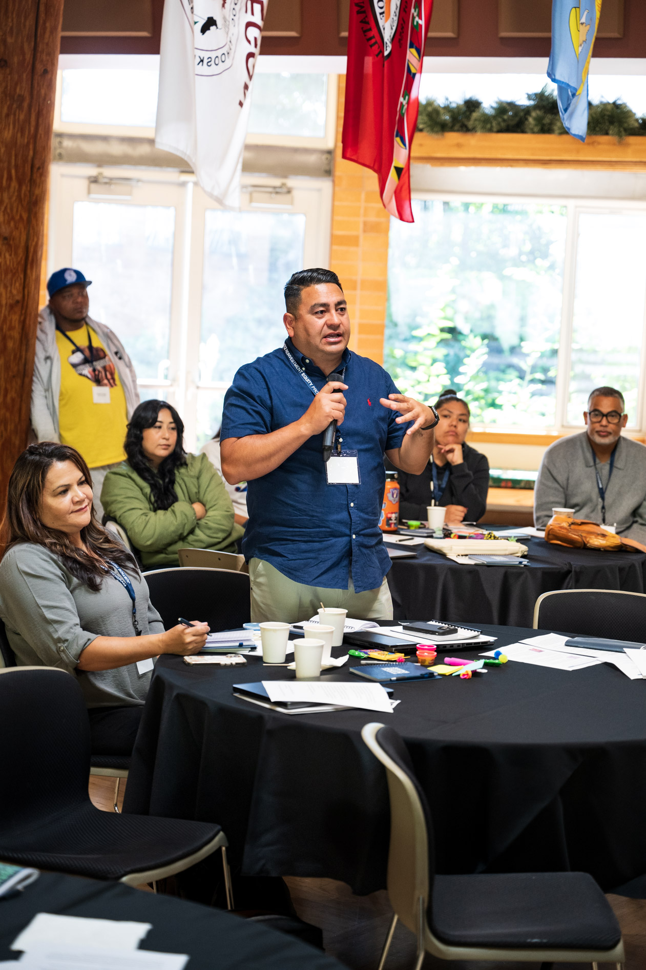 A candid photograph of a man speaking into a microphone to JREP grantees at the Northwest Health Foundation convening event.