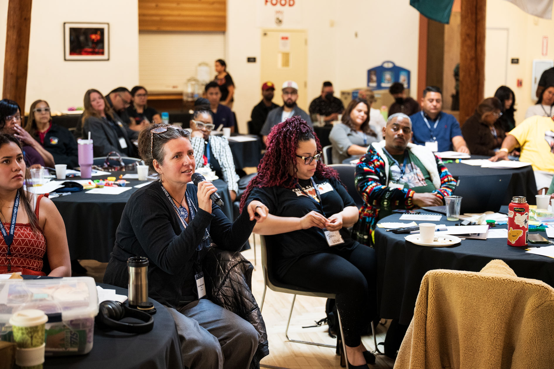 A candid photograph of a woman speaking into a microphone during a working session with JREP grantees at the Northwest Health Foundation convening.