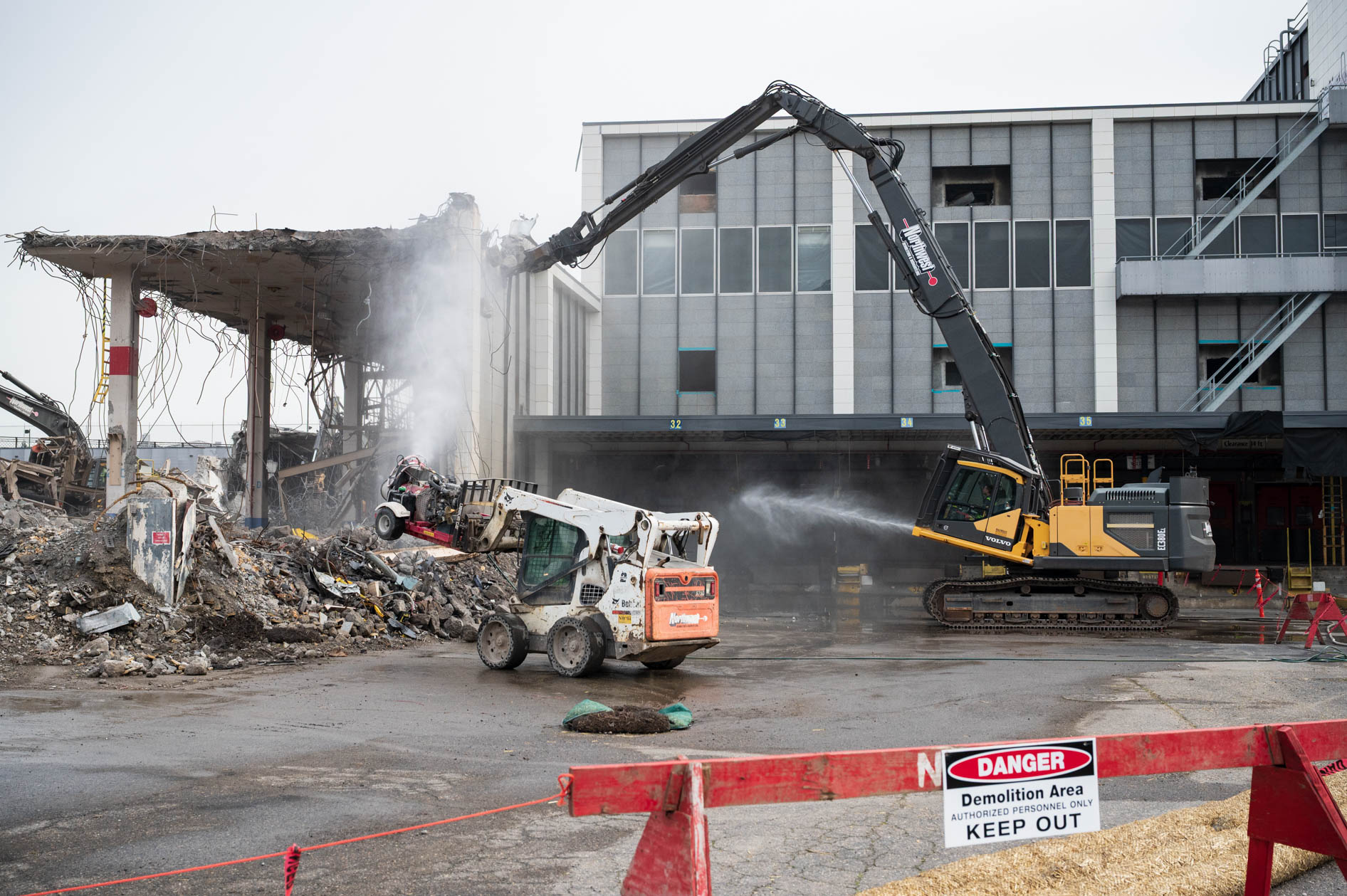 Event photography capturing the demolition of the former downtown Portland post office, showing an excavator and heavy machinery tearing down the building.