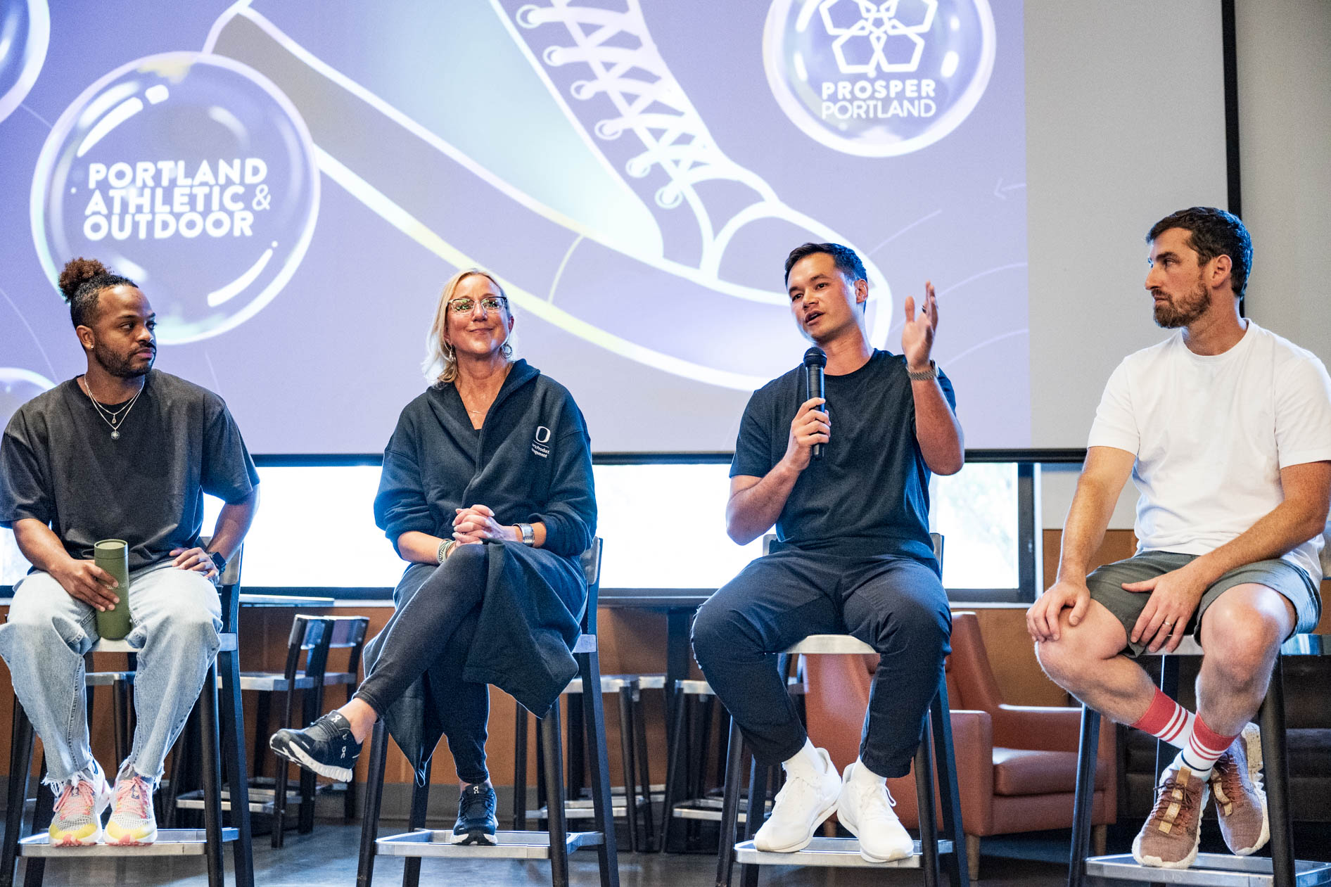 A candid photo of a panel discussion at Sneaker Week 2023 with industry leaders speaking on stage. This showcases conference photography by a Portland event photographer.