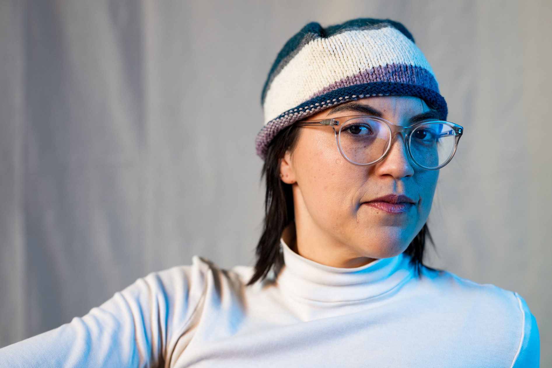 A professional inclusive portrait of a person wearing a custom-knit striped beanie and glasses. This highlights creative portraits in Portland, Oregon.