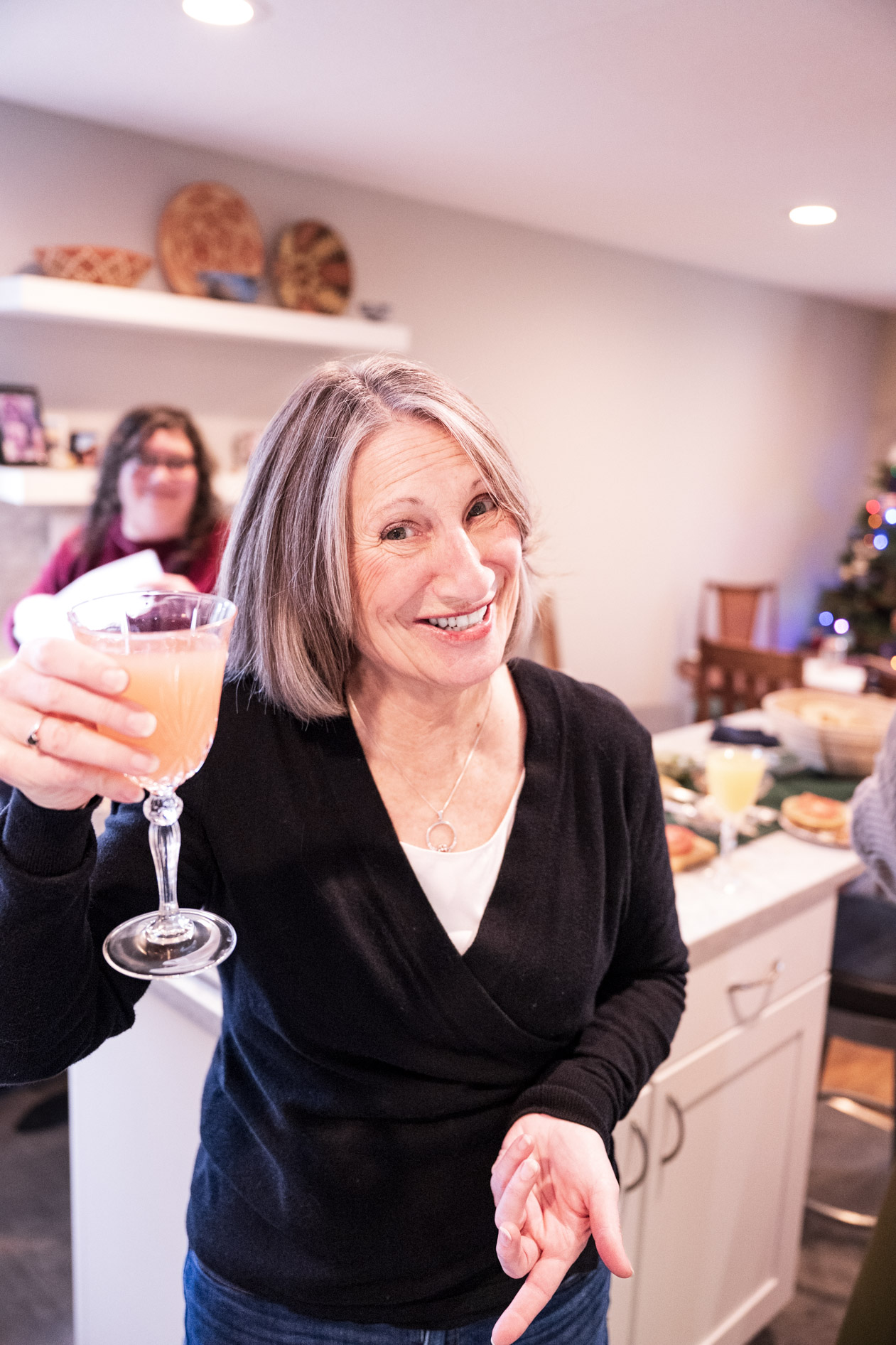 A smiling person holding a cocktail glass, posing in a kitchen during a holiday inclusive family photography session in Beaverton, Oregon.