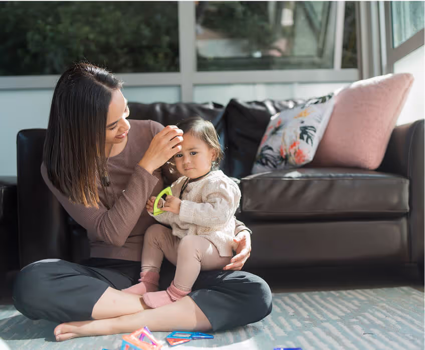 A woman sitting on the floor with a baby.