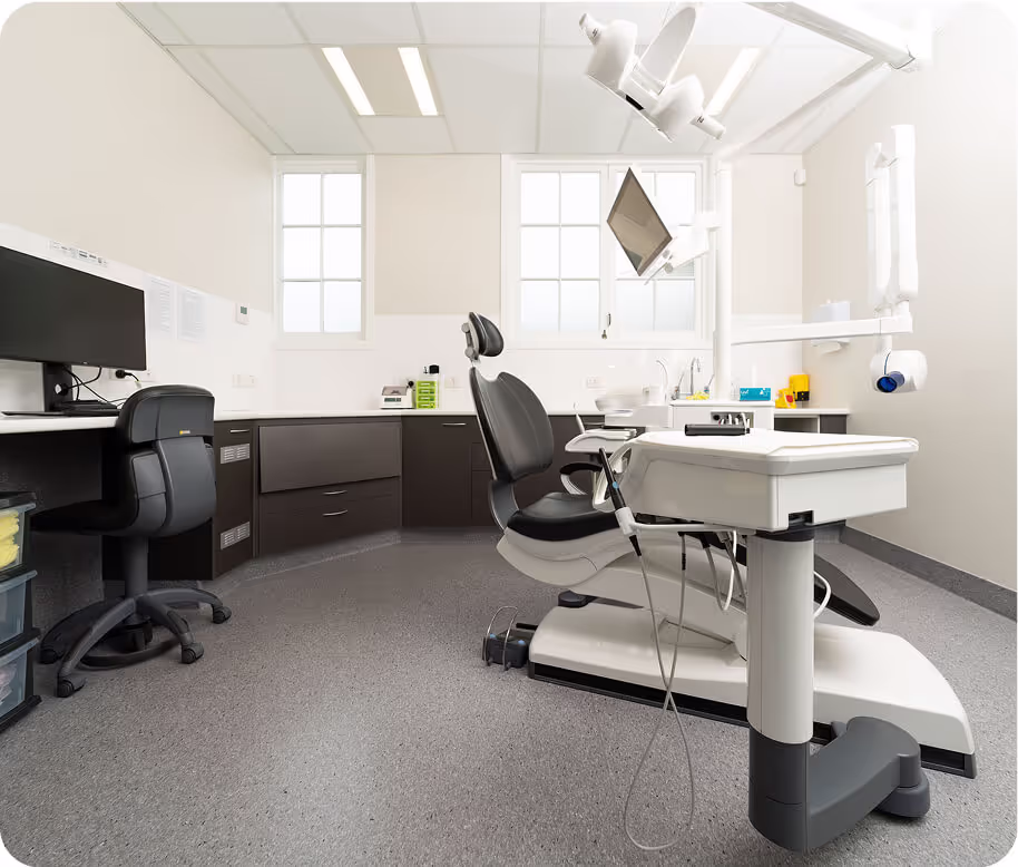 A dentist office with a white desk and a black chair.