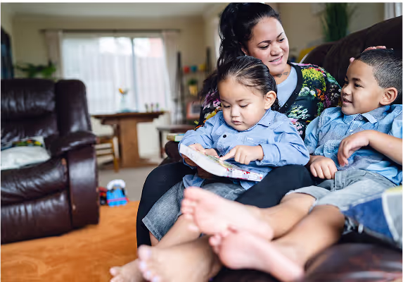 A woman and two children are sitting on a couch.