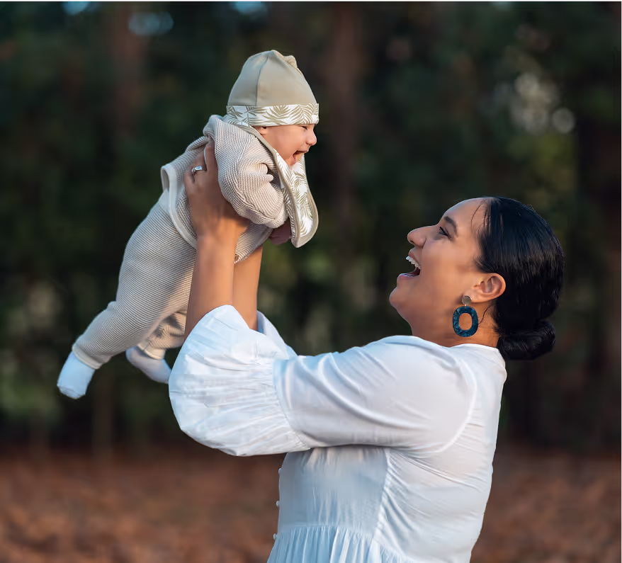 A woman holding a baby in a white shirt.