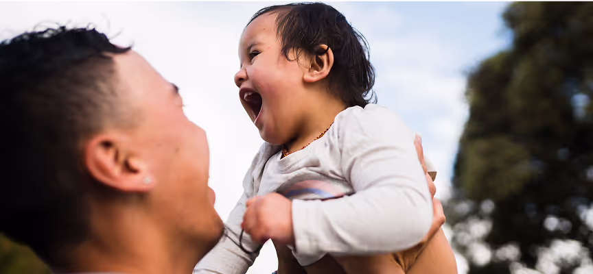 A man holding a baby with a smile on his face.