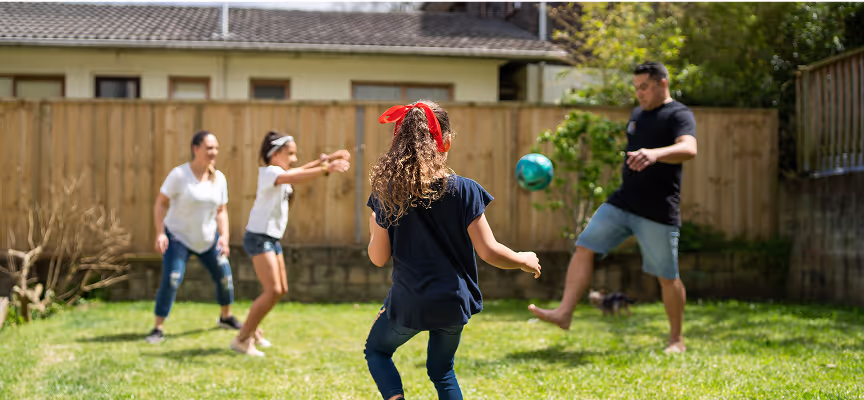 A young girl in a blue shirt and red bow is playing with a ball.