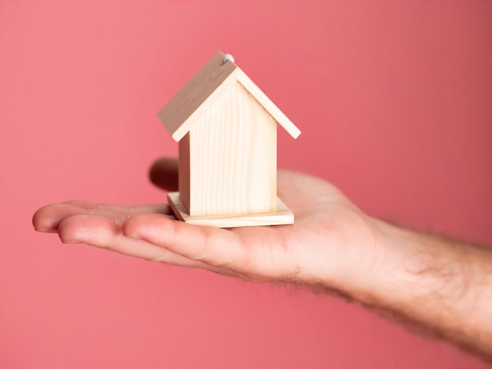 Person Holding Brown Miniature Wooden House