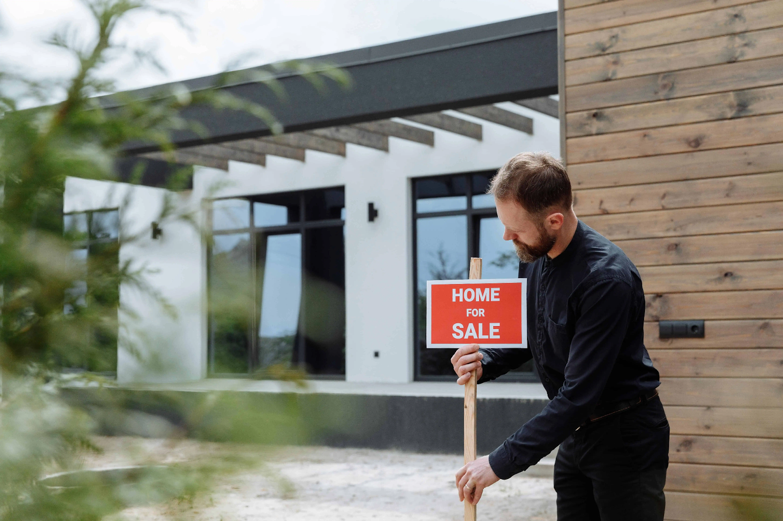 a  man holding a home for sale signage
