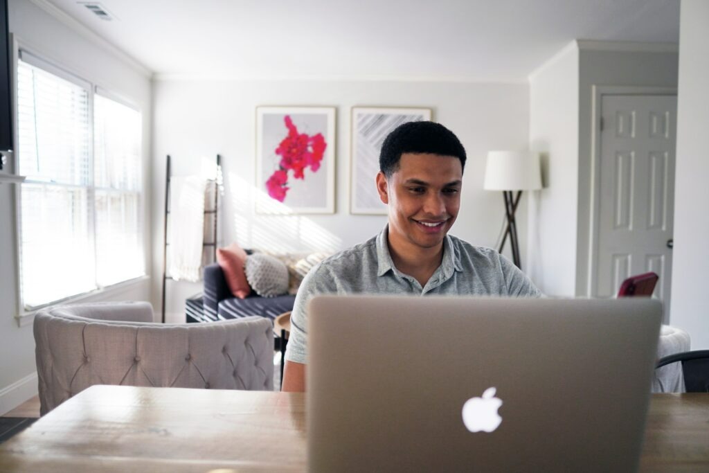 a man smiling using macbook
