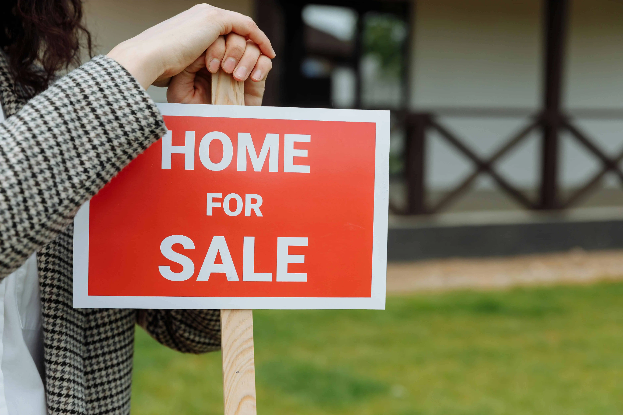 Buying a foreclosed house: woman holding a home for sale sign