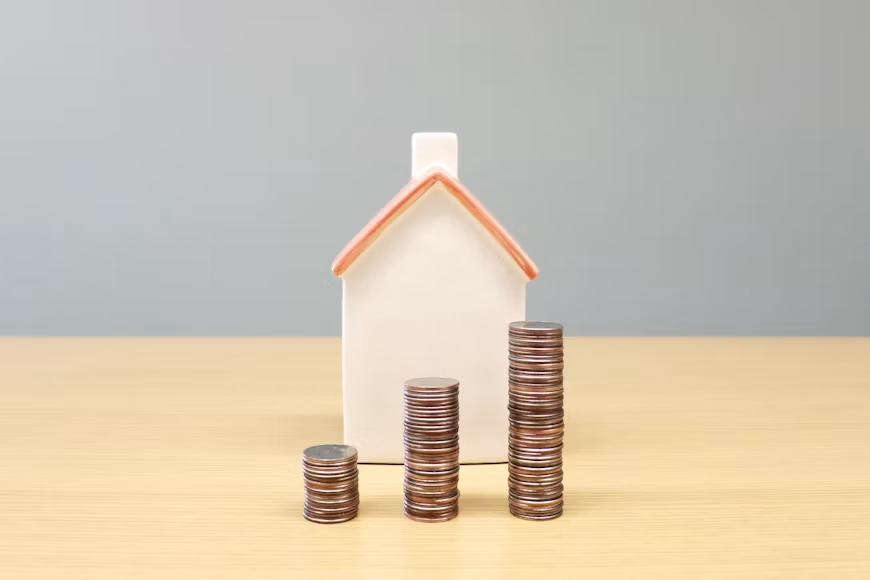 House model with stacked coins representing mortgage costs
