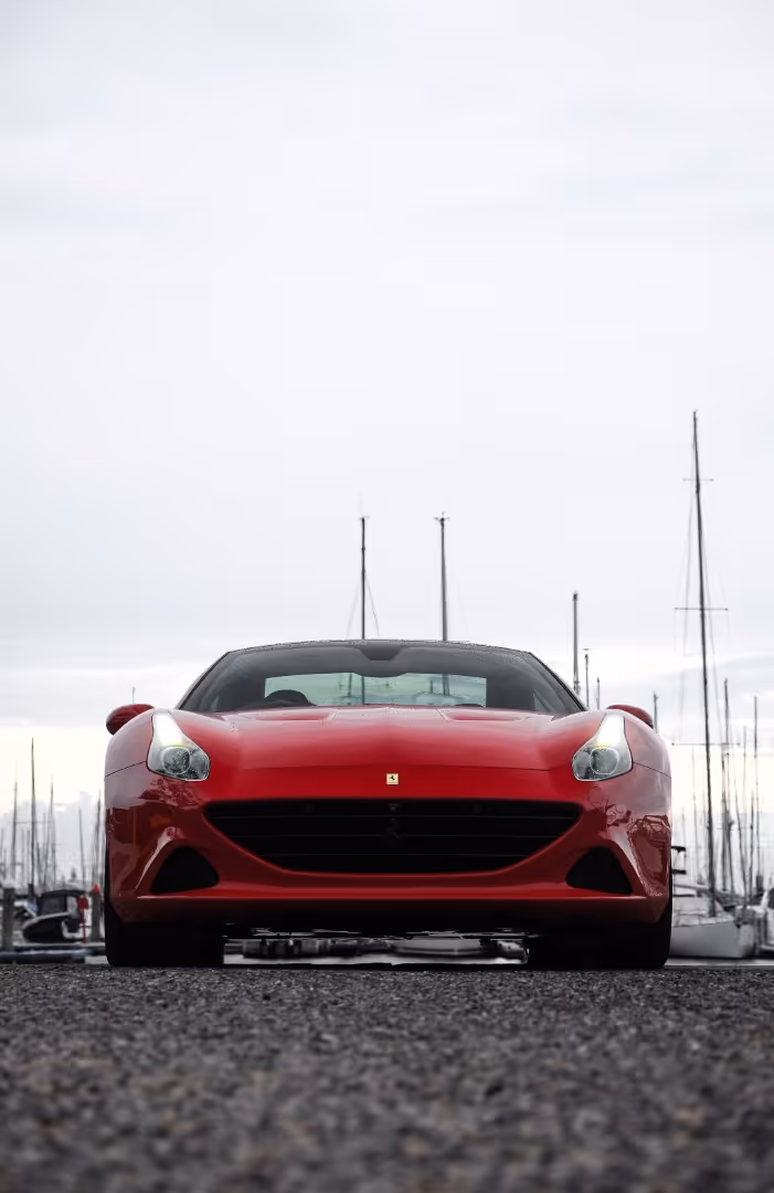 Red luxury Ferrari car parked on wet asphalt, automotive lifestyle photography.