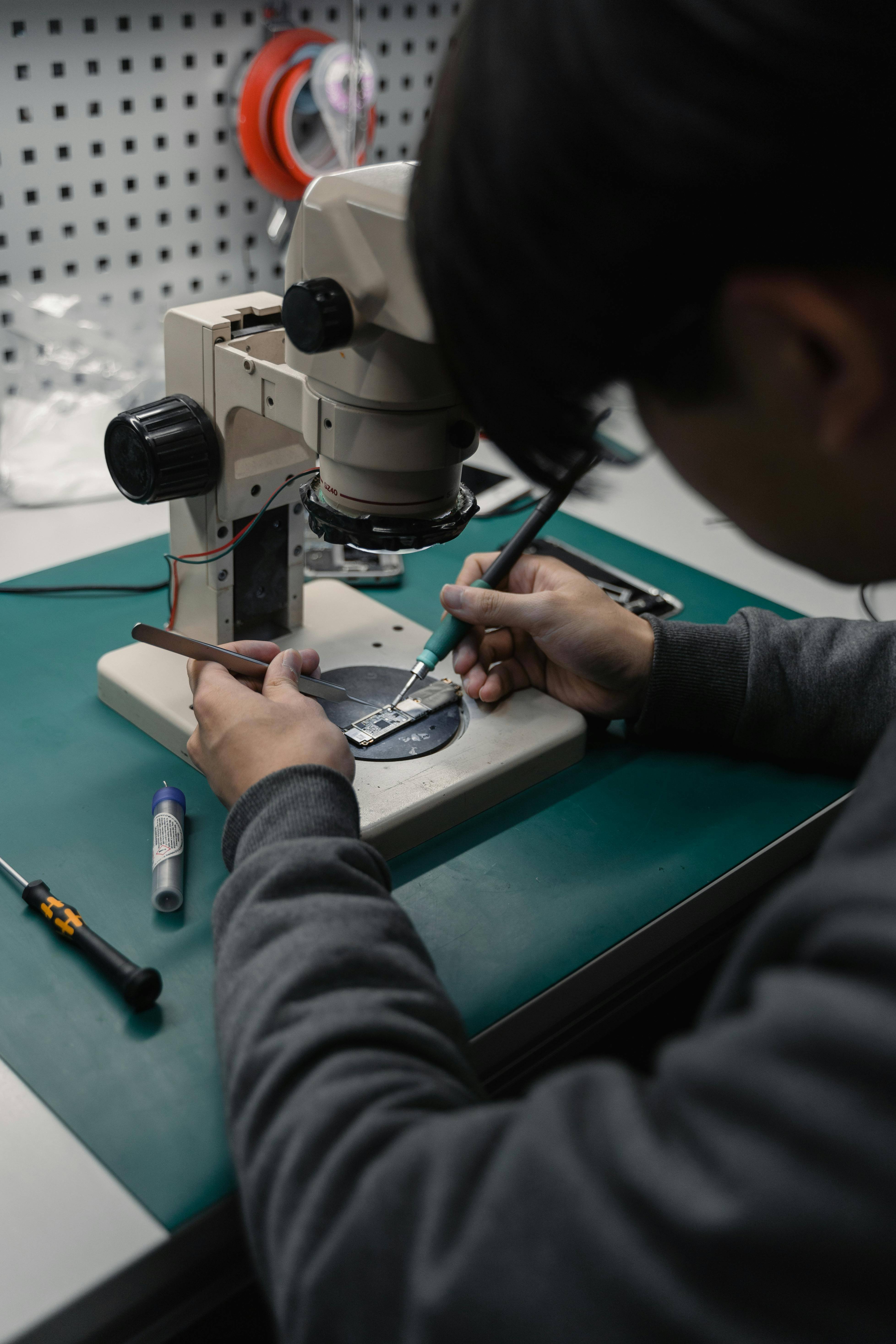 A technician works with precision tools under a microscope.