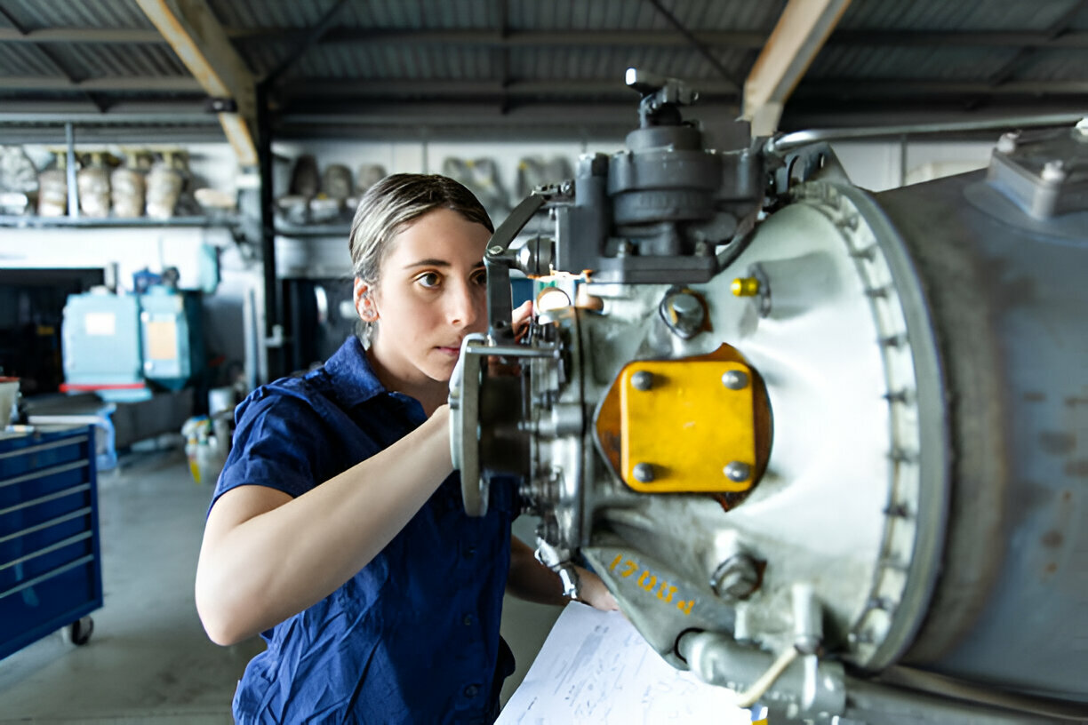 Engineer in blue uniform examining large industrial machinery in workshop