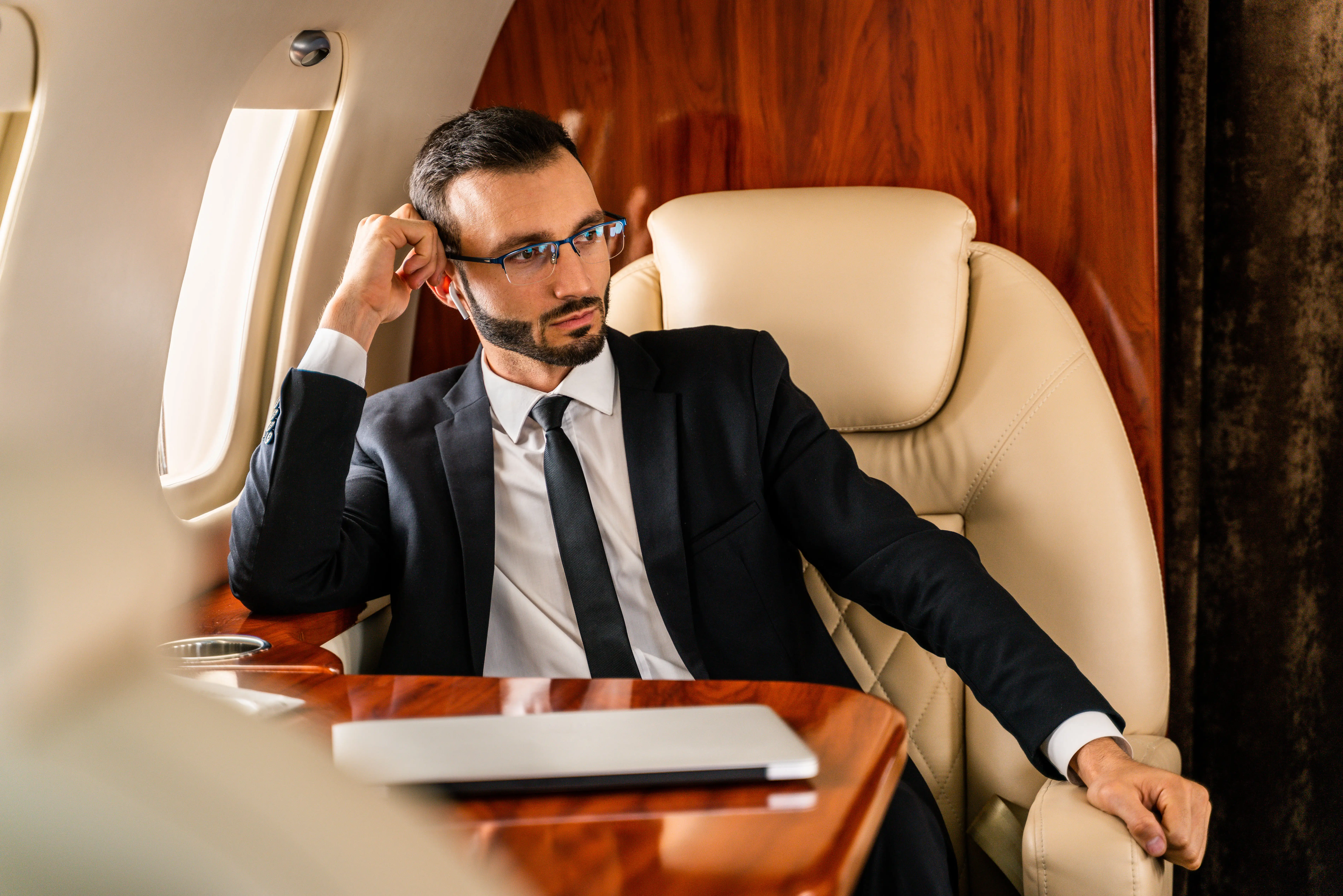 Business professional sitting in first-class airplane seat, looking thoughtful