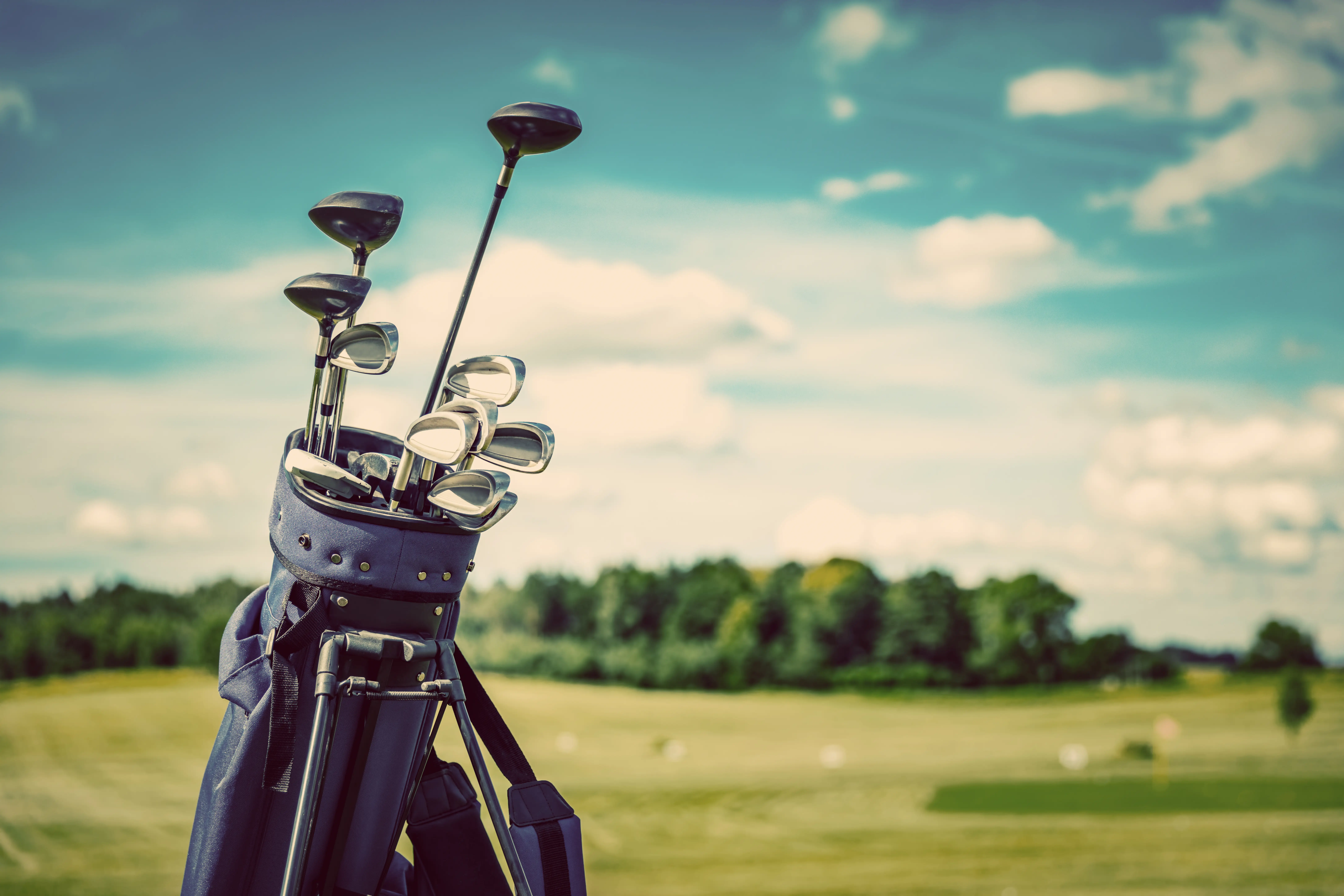 Golf clubs rested on a fairway with a blue sunny backdrop