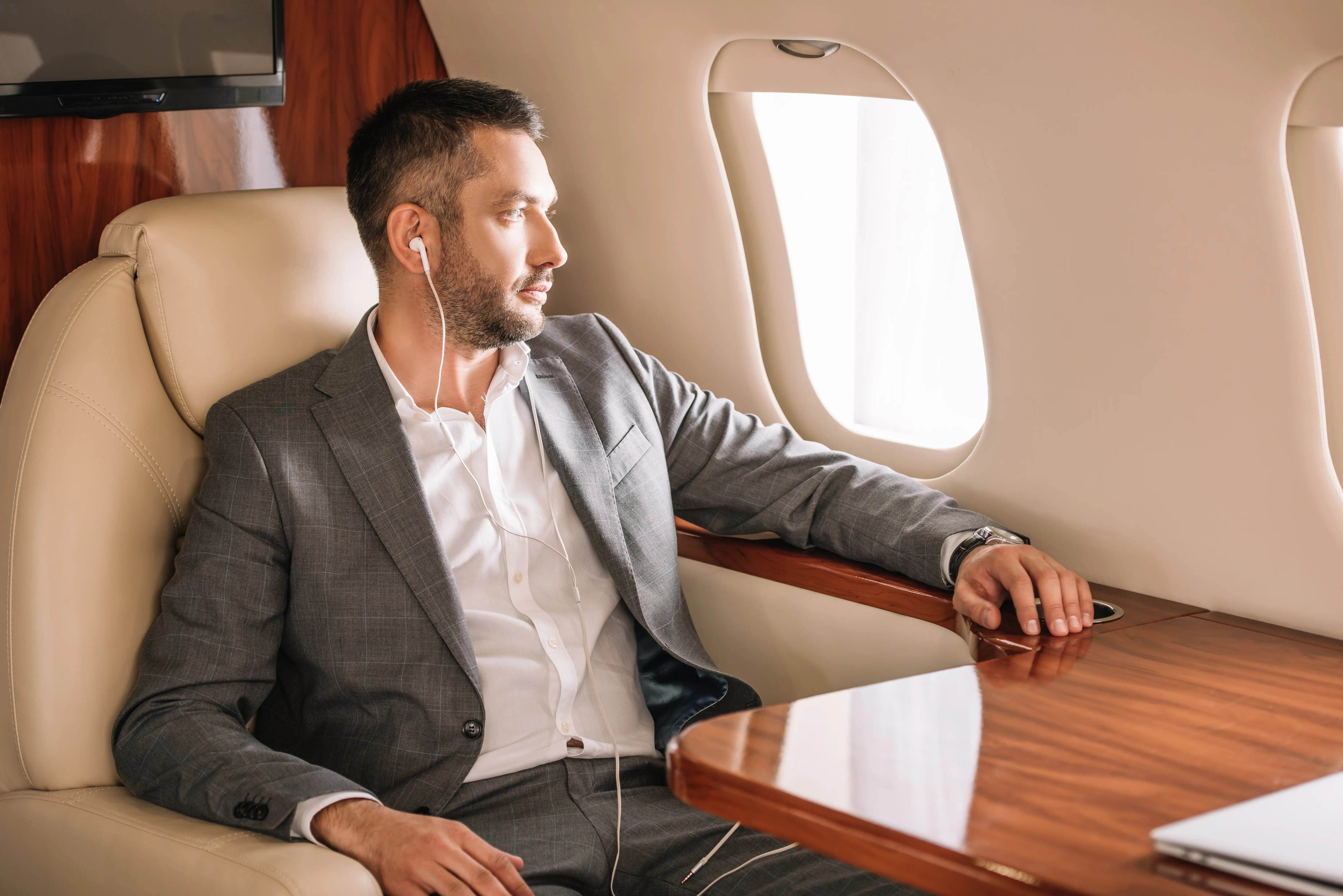 Business professional relaxing with earbuds in first-class airplane seat