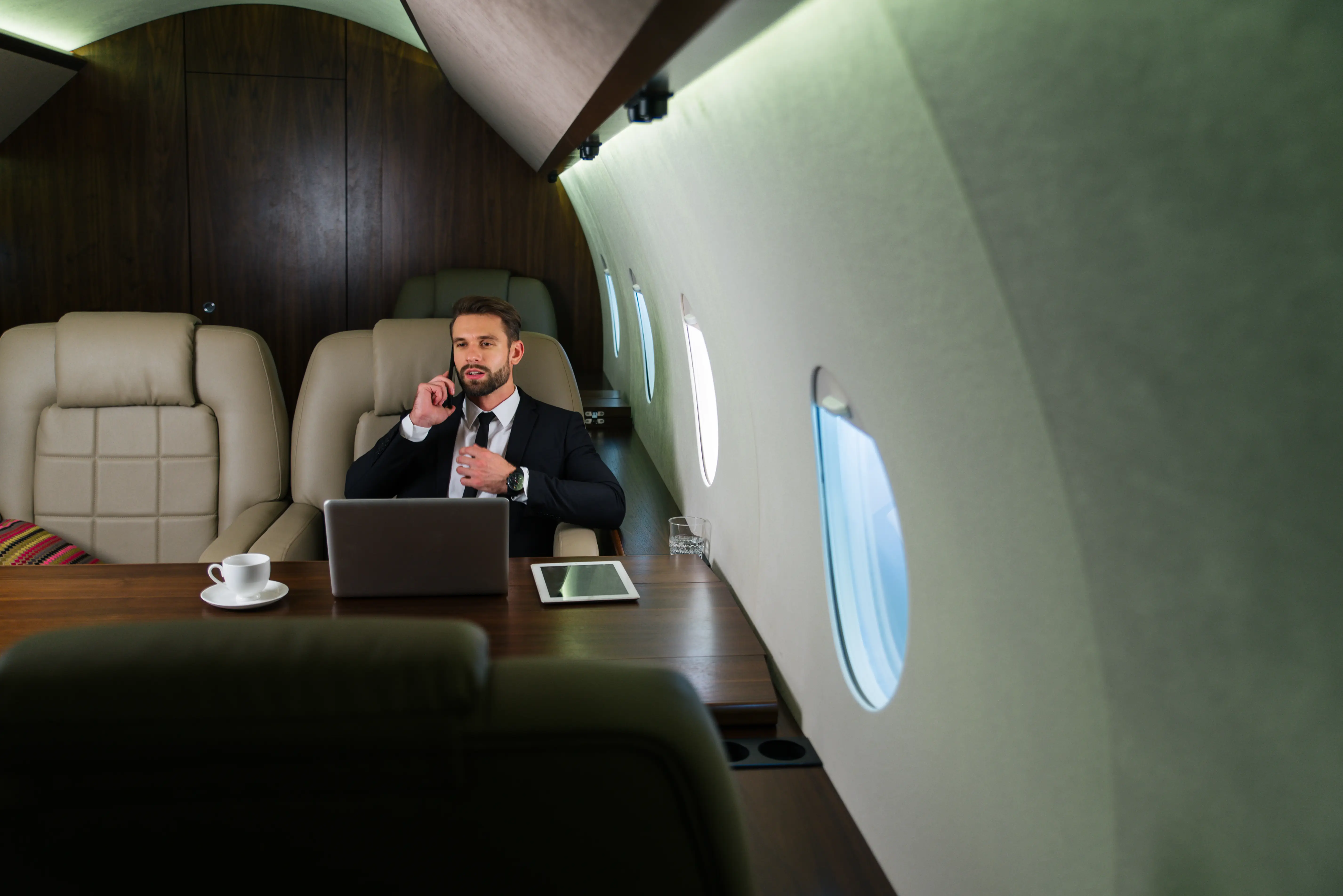 Business professional on phone inside luxurious private jet workspace