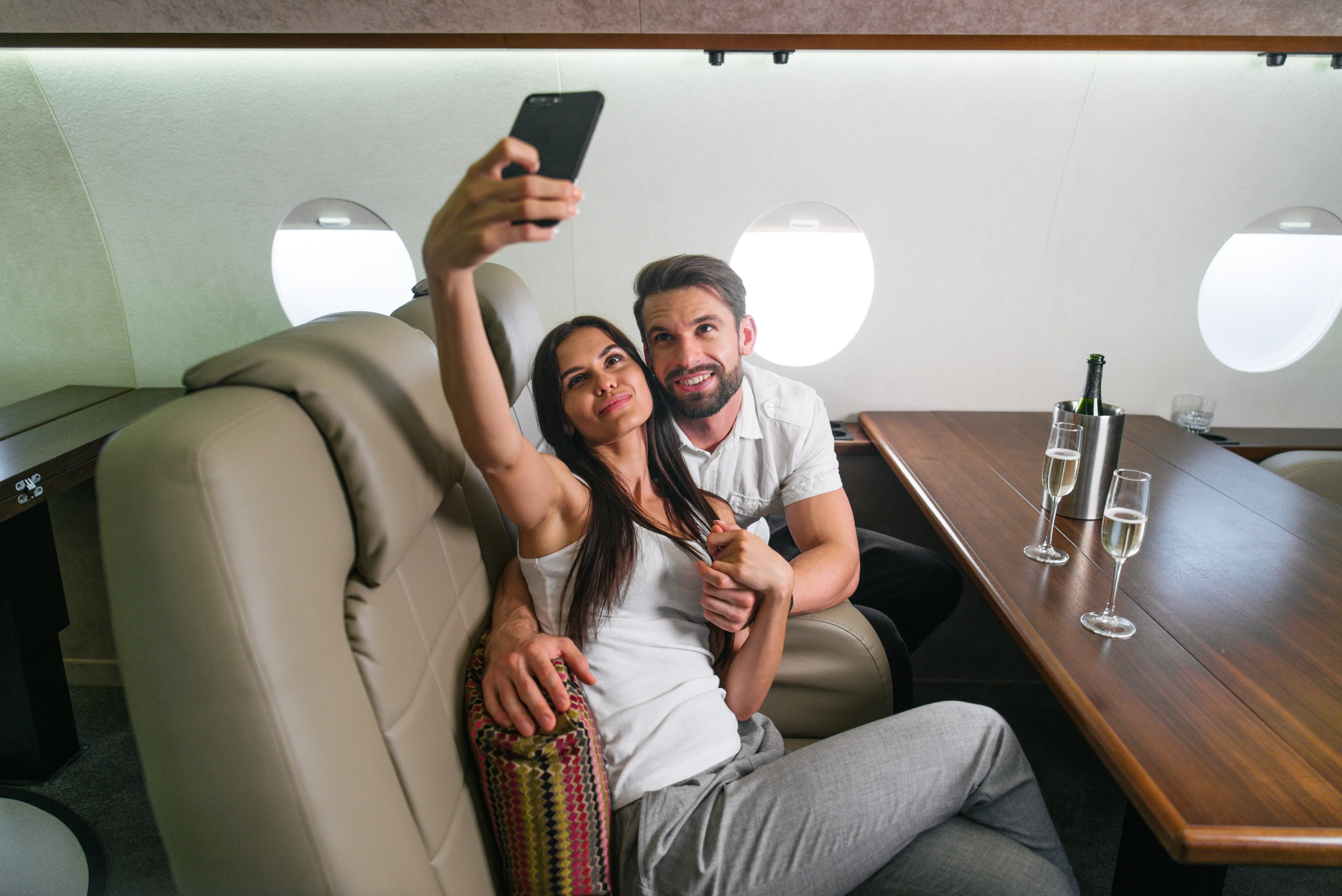 Couple taking selfie and enjoying champagne in luxury private jet