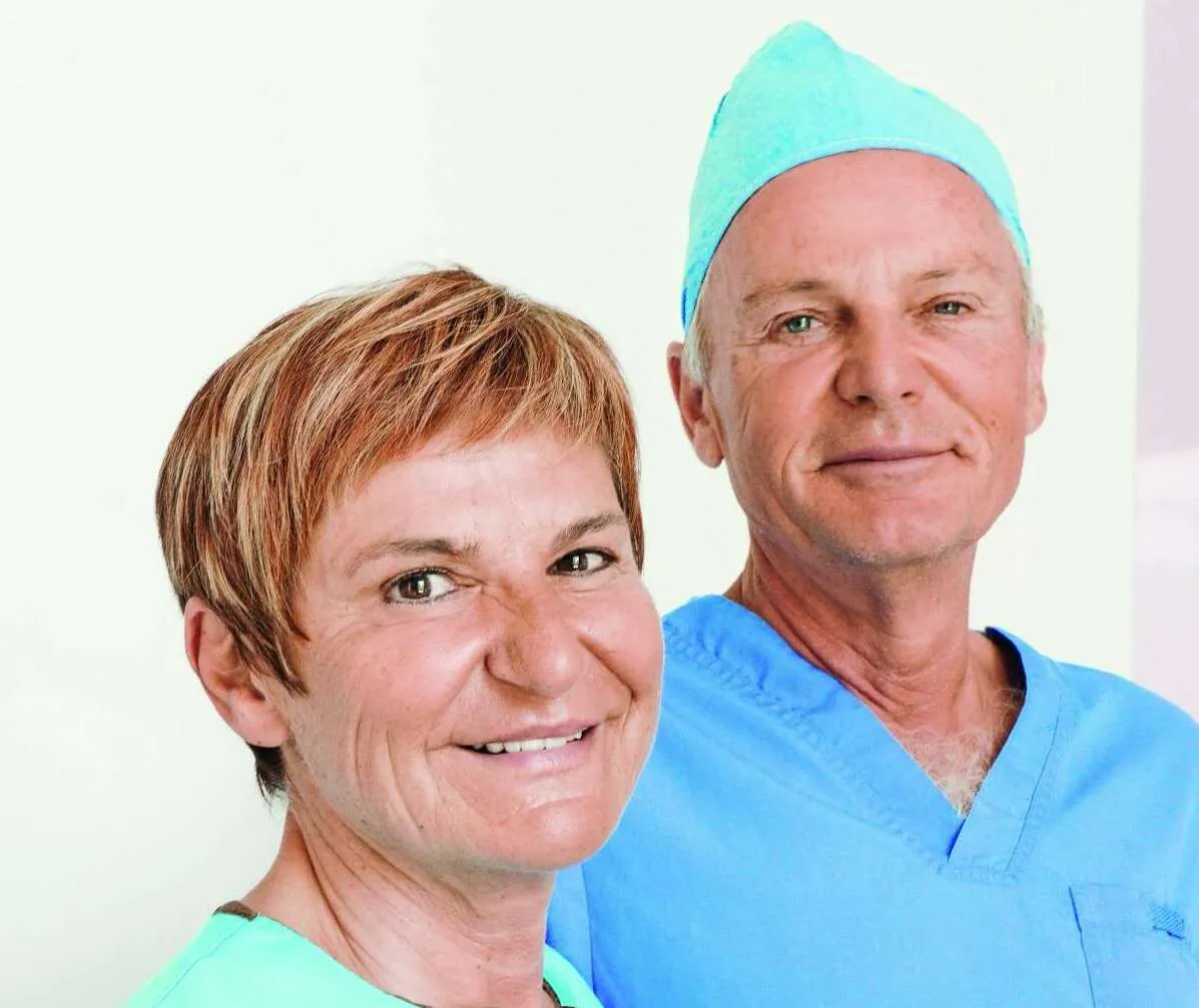 Nasmejana ženska in mož v zdravstvenih uniformah na svetlem ozadju.