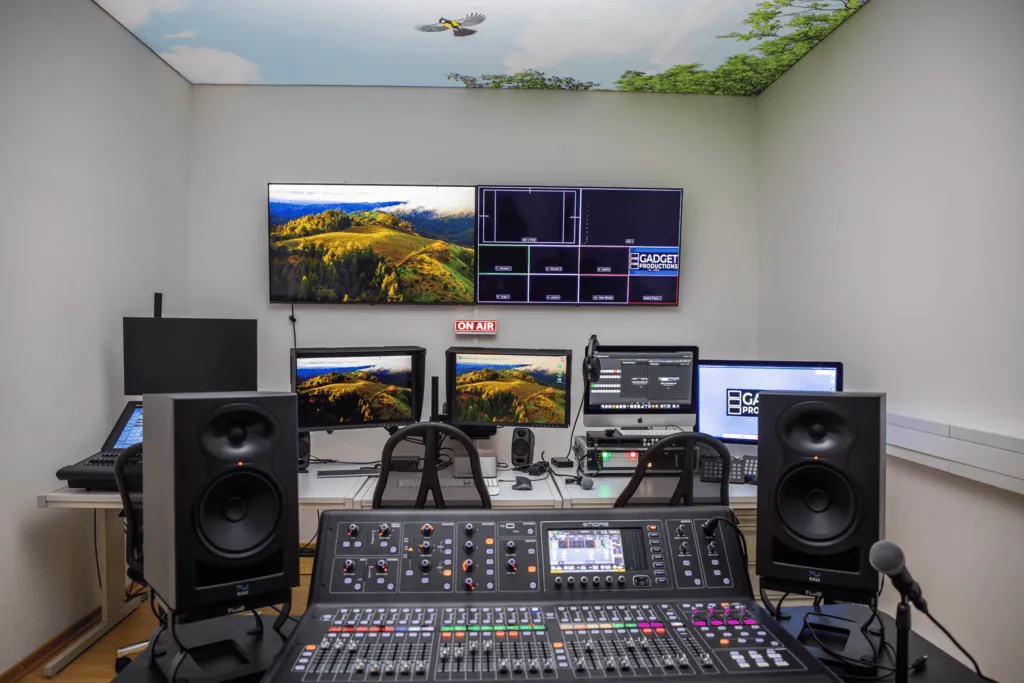 Modernes Tonstudio mit Mischpult, Lautsprechern, mehreren Monitoren und einer Decke mit Himmel- und Vogelmotiv.