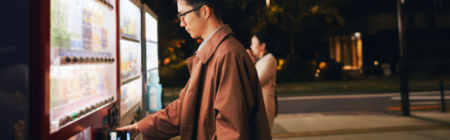 Man paying at vending machine at night