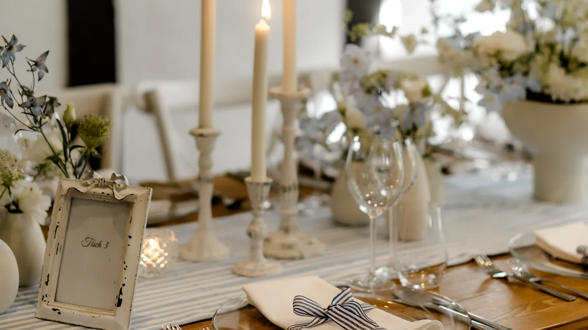 Festlich gedeckte Hochzeitstafel von PURE FLAIR in Weiß und Creme mit Kerzenleuchtern und Tischnummer im Fachwerkraum