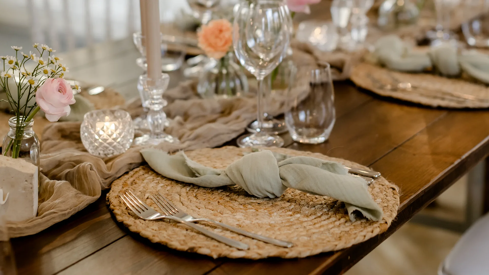 Hochzeitstafel von PURE FLAIR mit Bastteller, salbeigrüner Serviette, Kerzen und Blumen in Rosé und Apricot