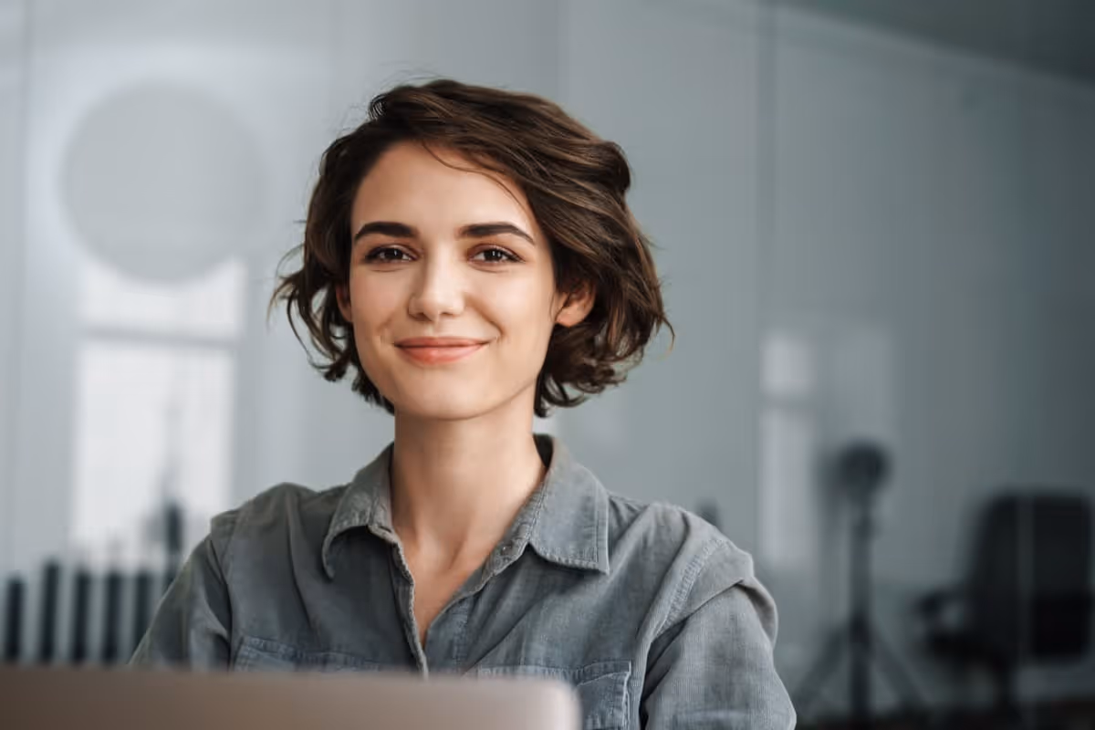 Image of young joyful woman smiling while working with laptop in office; employee development concept|Two workers smiling happy working sitting on desk at the office; employee development concept|Manager discussing with colleagues in meeting at creative office; employee development concept