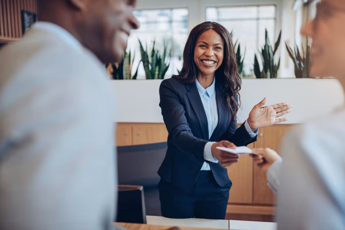 smiling businesswoman passes paper to employee; benefits programs concept|Smiling man working on laptop in modern office|Young woman behind laptop smiling at camera