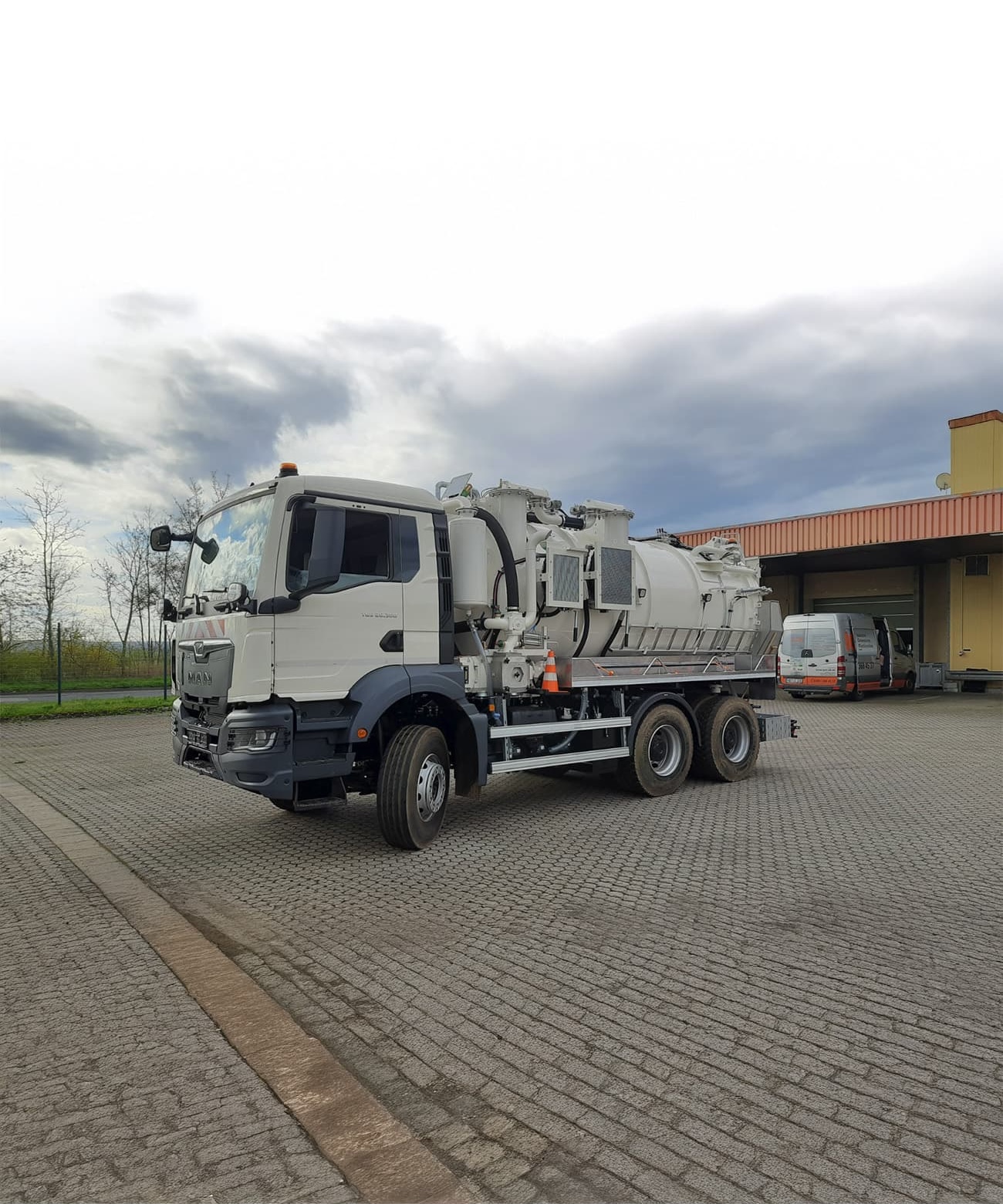 Modernes Spezialfahrzeug mit Saugtank für industrielle Einsätze, geparkt vor dem Firmengebäude.