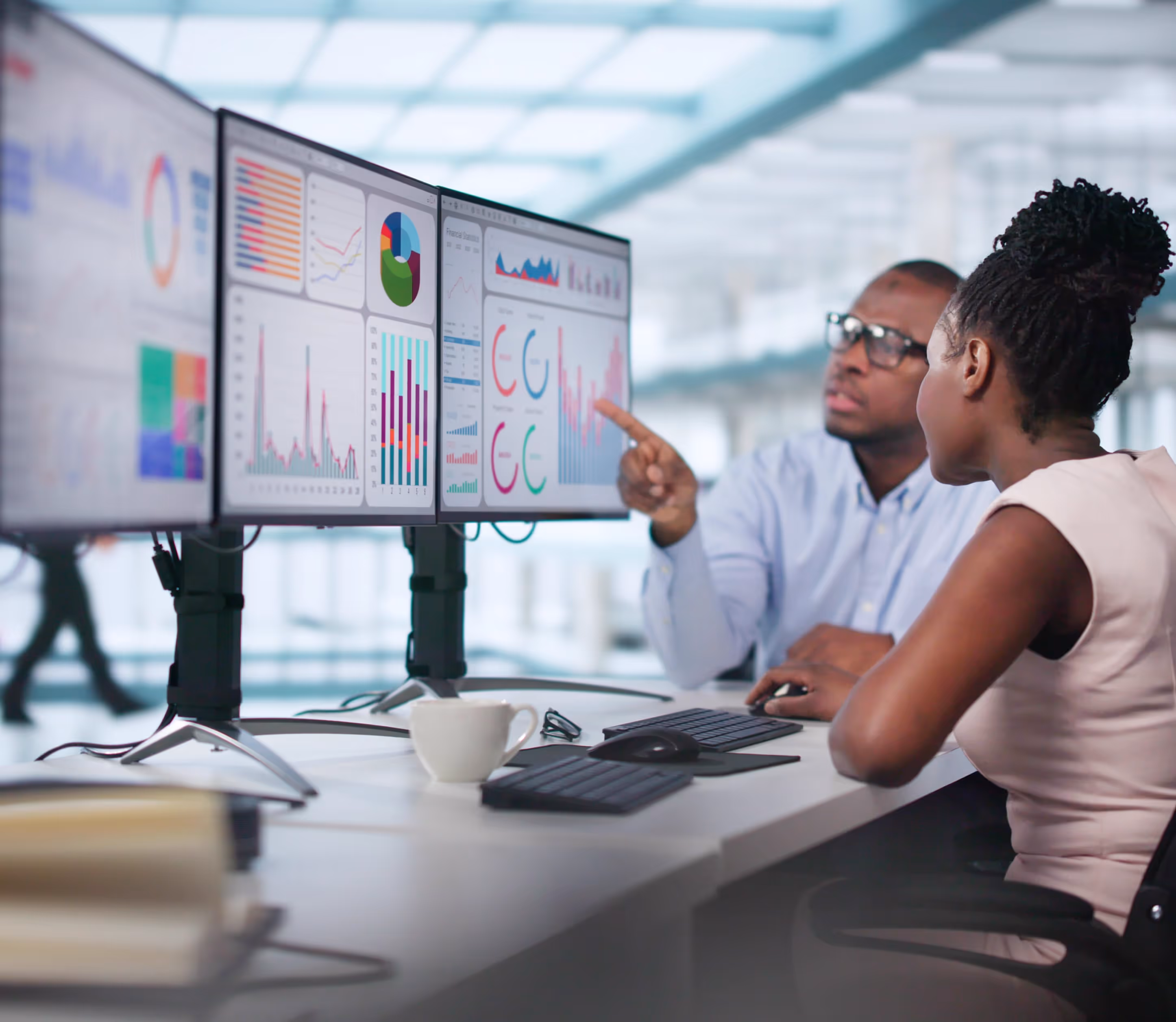 A couple of people sitting at a desk in front of a computer.