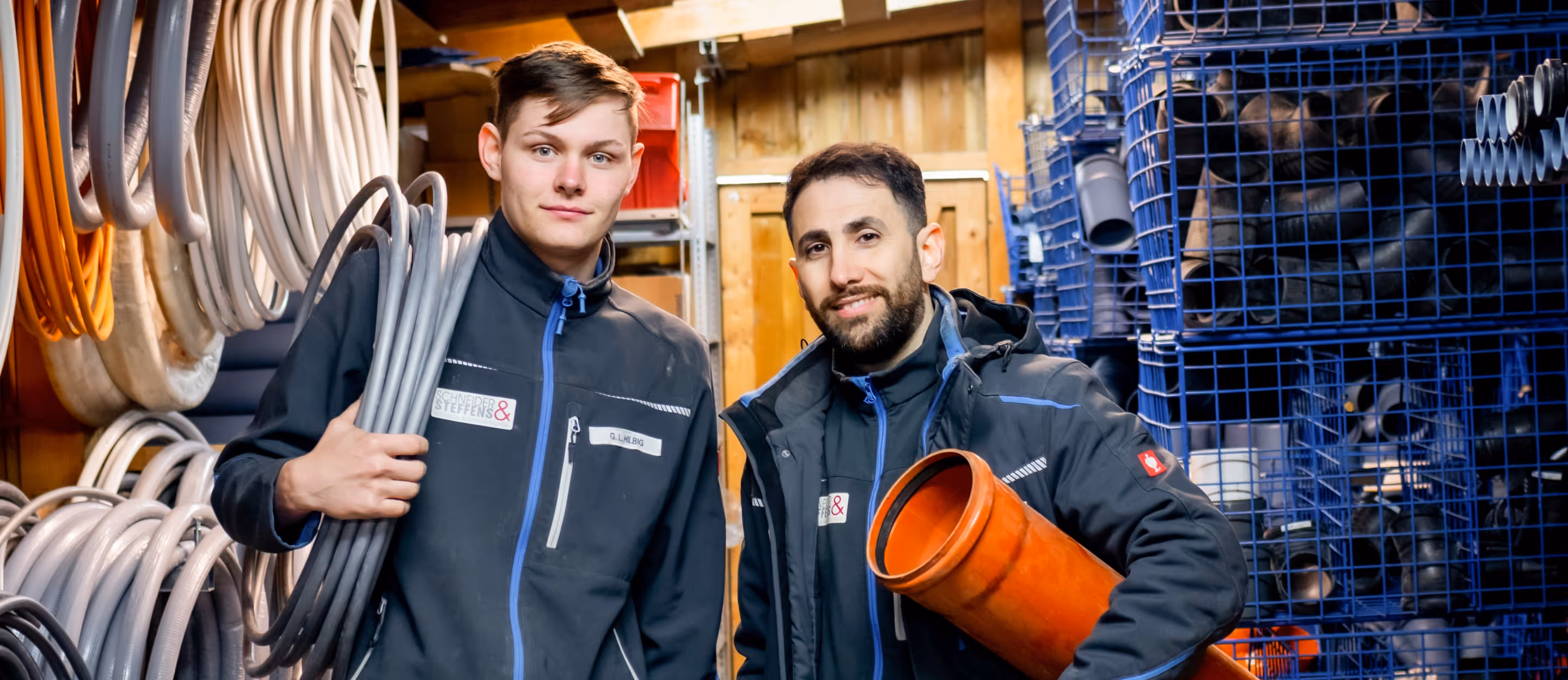 Zwei Schneider & Steffens Mitarbeiter im Lager mit Schlauch und Rohr.