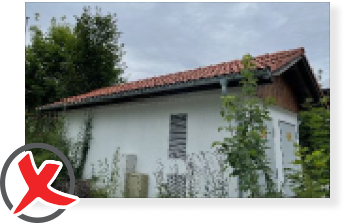 Kleines Gebäude mit beschädigtem roten Dach.