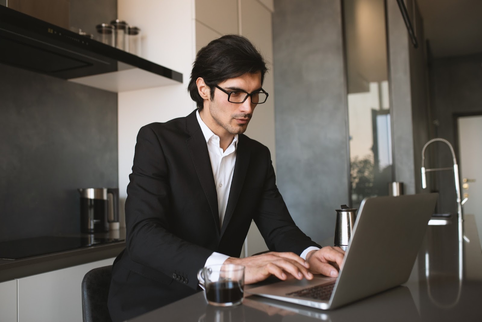 A man wearing eyeglasses using his laptop