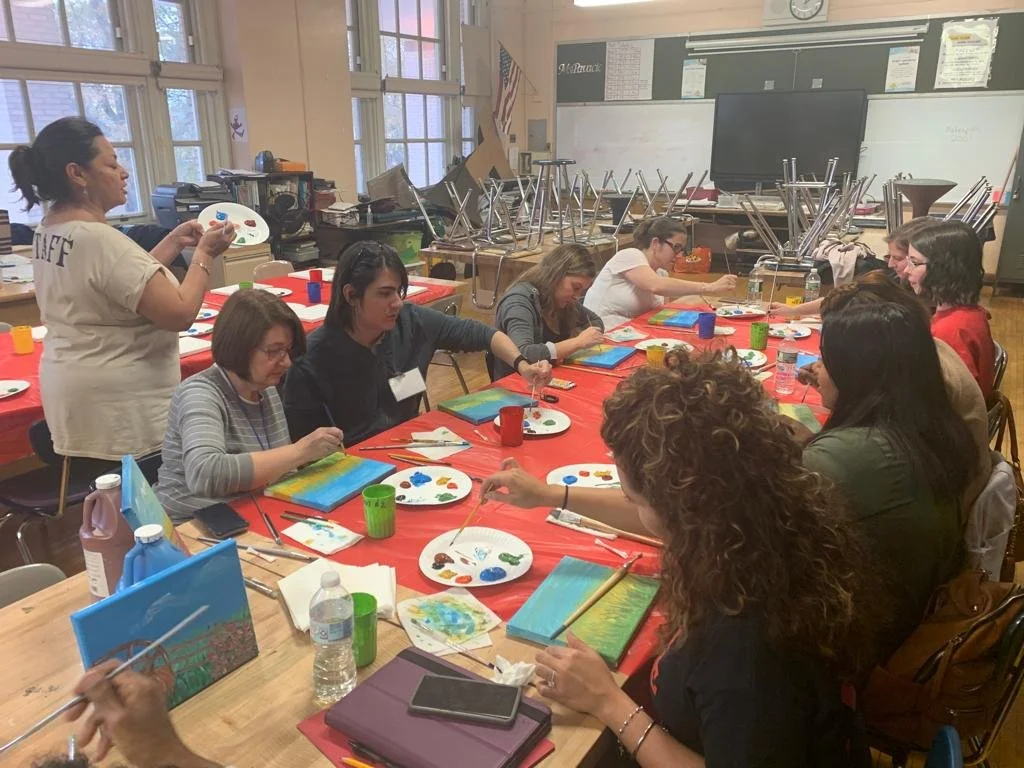 Adults participating in a painting workshop in a school classroom