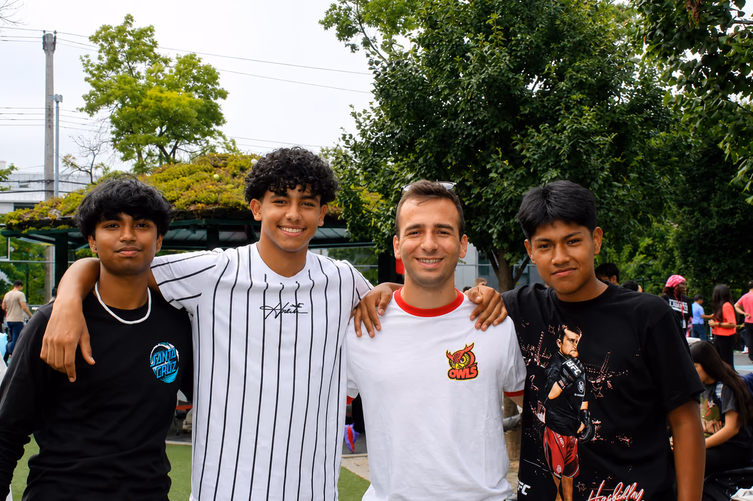 Four smiling students posing together outdoors at a school event