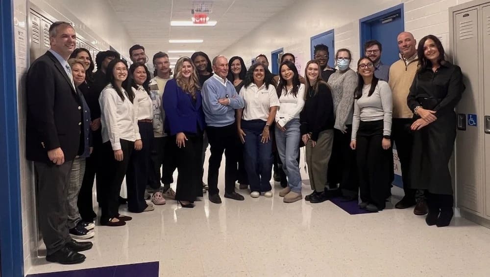 Group of staff and visitors posing together in a school hallway