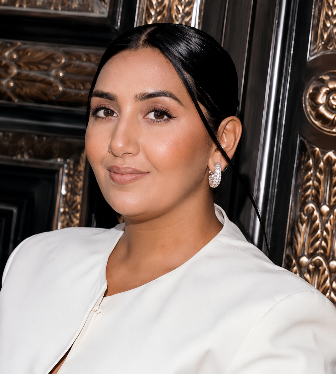 Sofia Ikram smiling in a white blazer against ornate backdrop