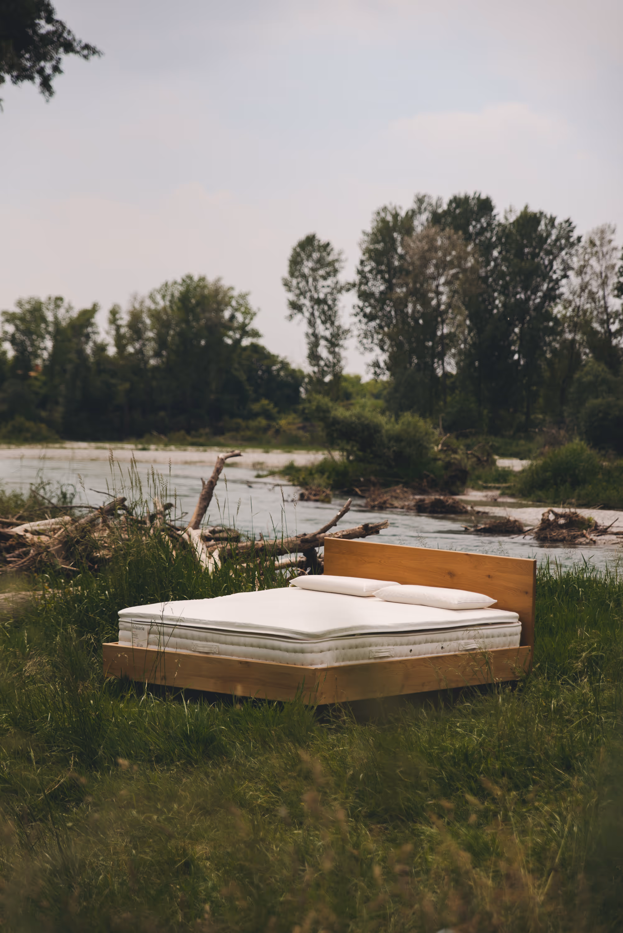 Letto con materasso Materia piazzato in mezzo a l'erba verde in riva ad un torrente.