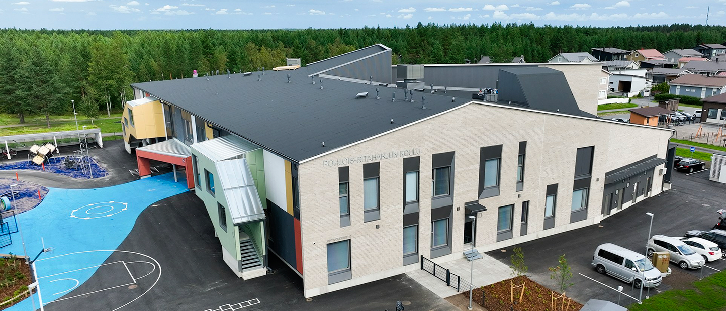 Valkoinen koulurakennus kuvattuna ilmasta käsin