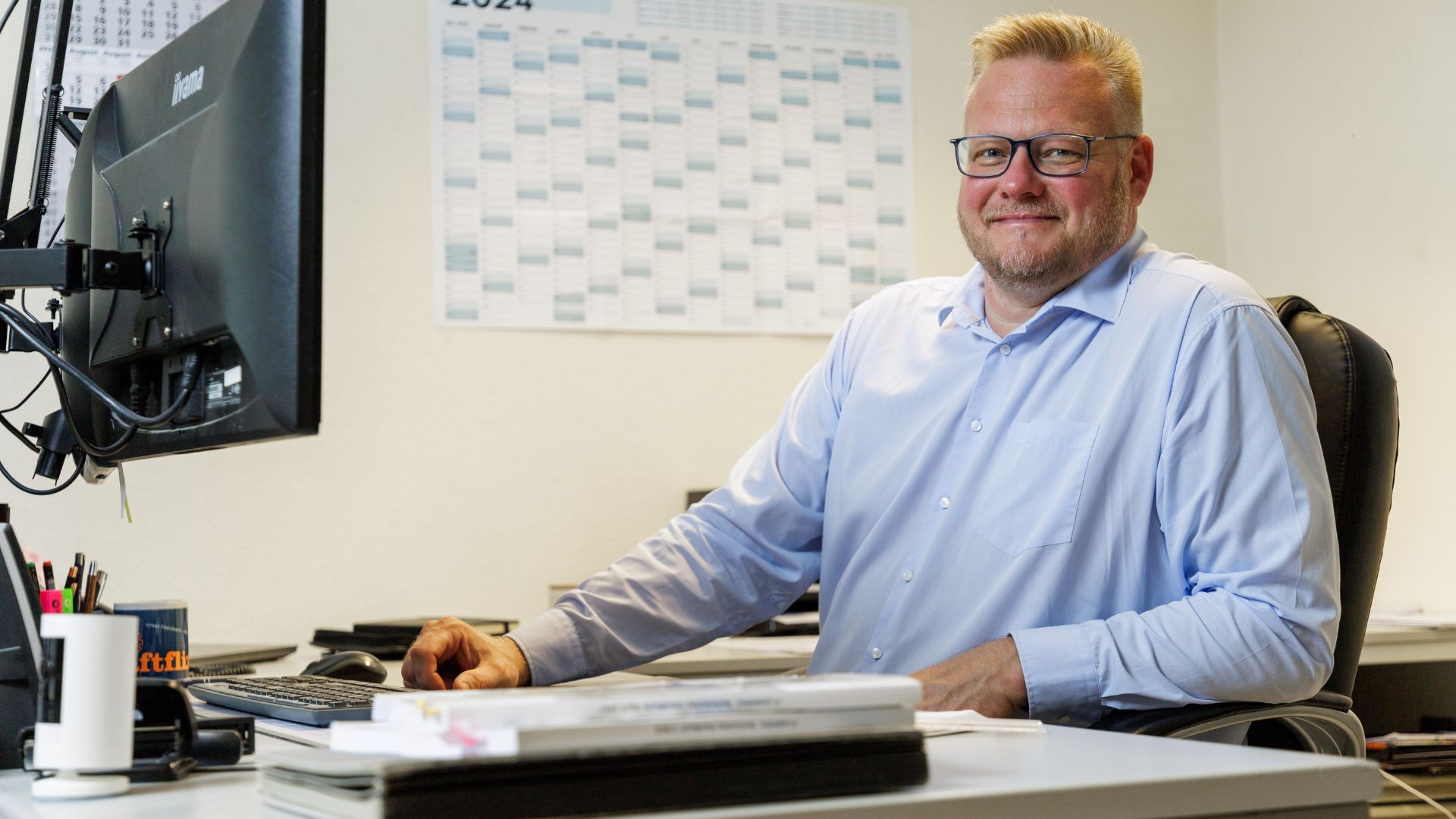 Mann sitzt im Büro am Schreibtisch und arbeitet am Computer.