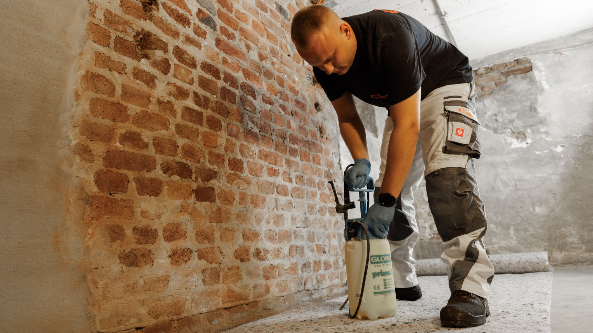Handwerker trägt Abdichtungsmittel mit Sprühgerät auf