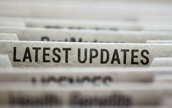 Close-up of the top edges of papers, with one visible with the title, latest updates