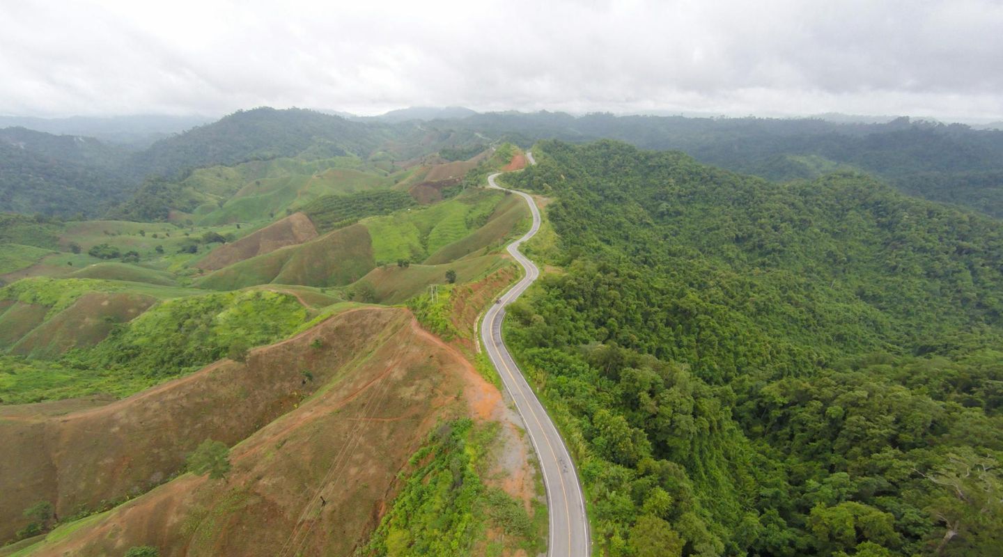Aerial view of a scenic mountain road surrounded by lush greenery